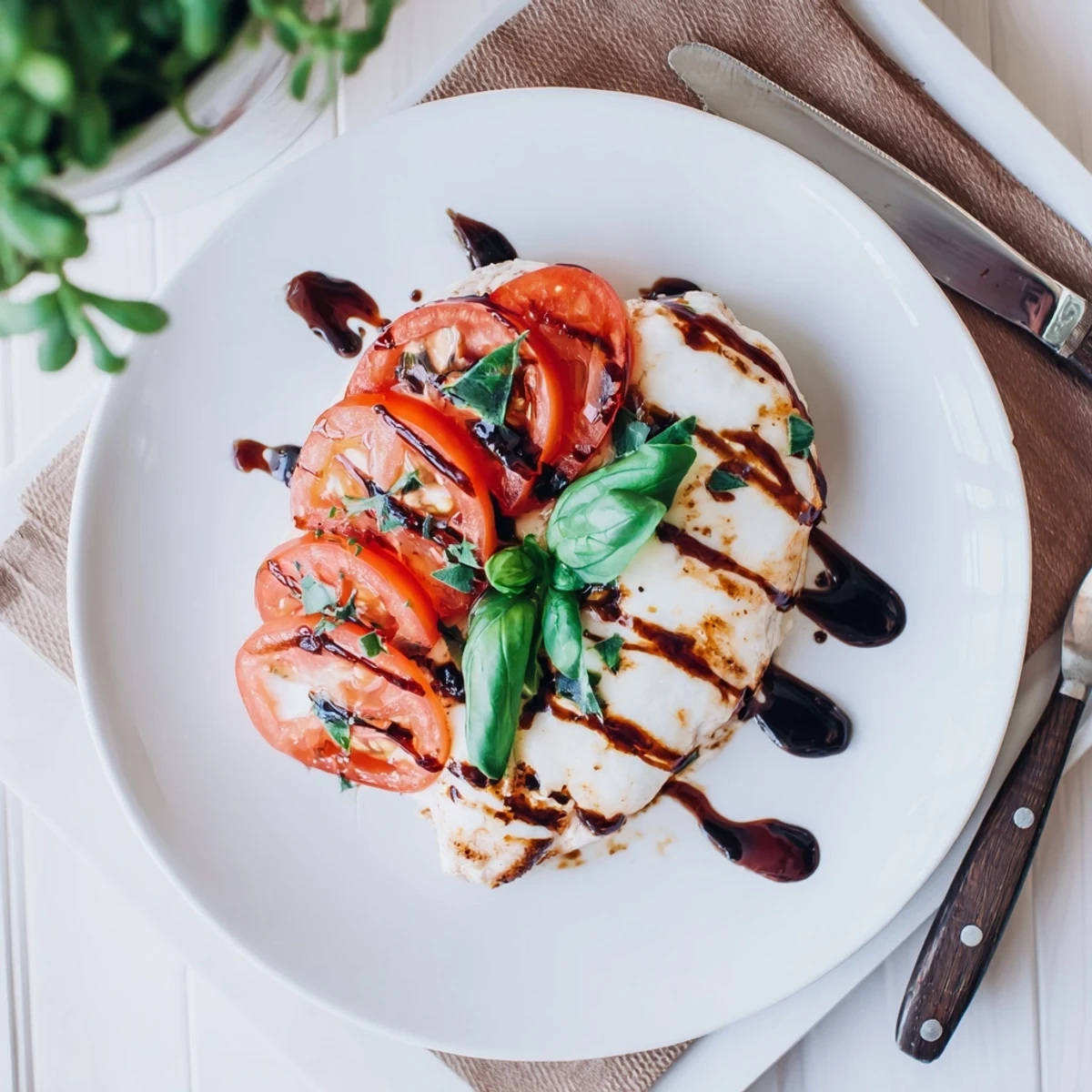 Italian-style baked chicken with balsamic marinade featuring melted mozzarella and garnish of fresh basil
