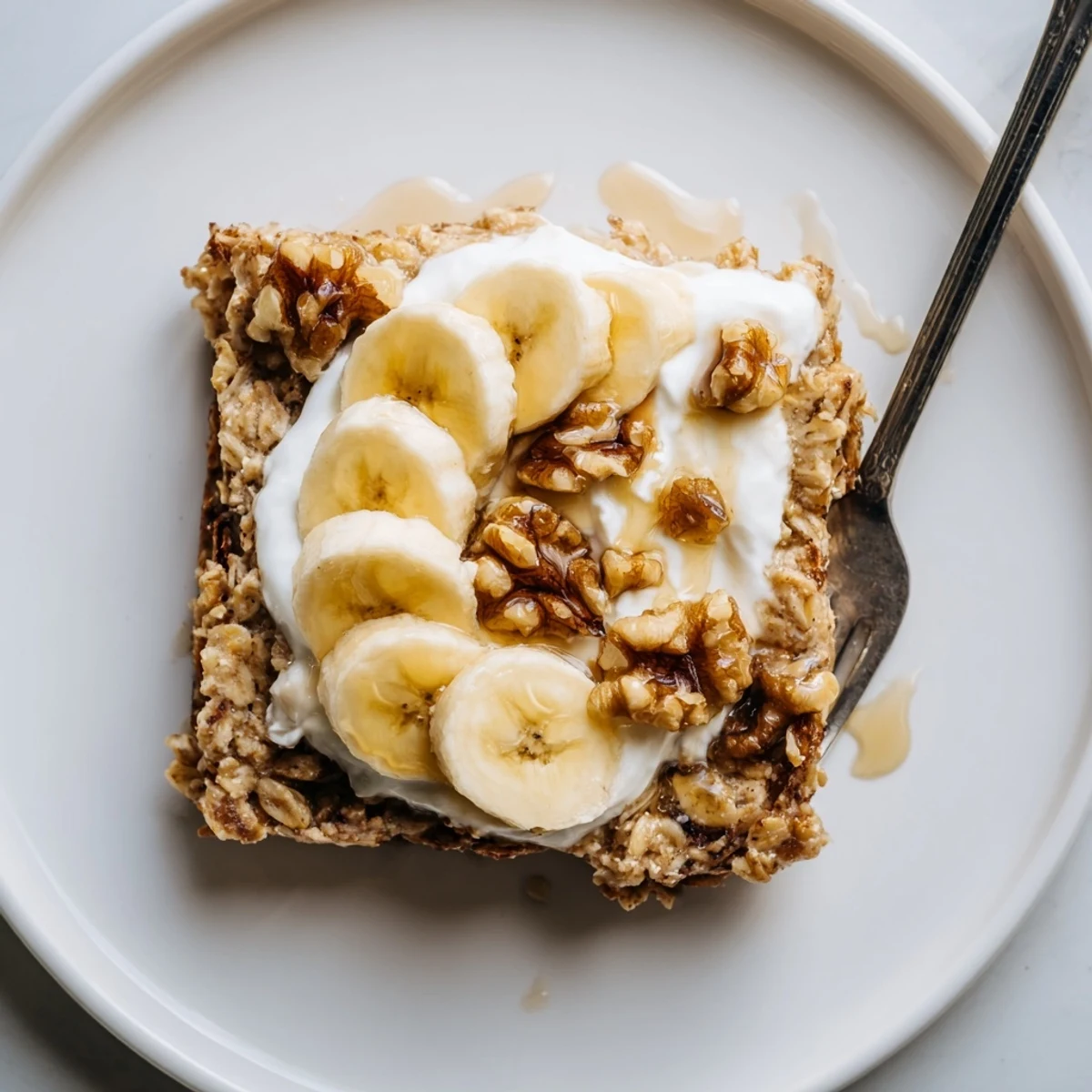 Warm cinnamon-spiced banana baked oatmeal drizzled with maple syrup and crunchy walnuts