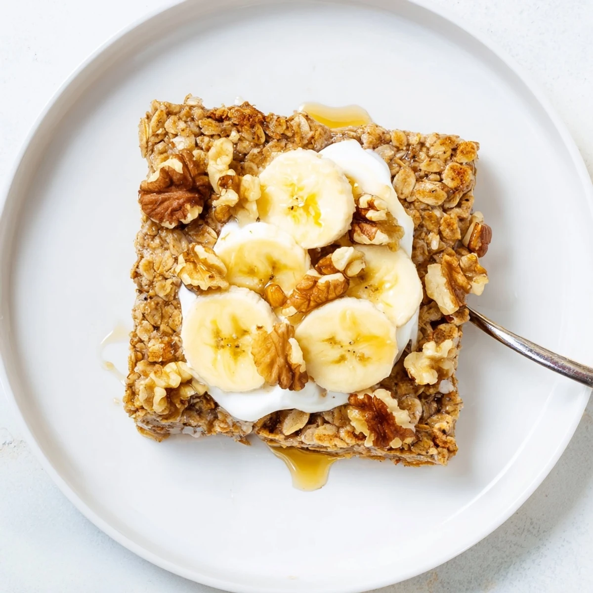 Wholesome banana baked oatmeal breakfast bake with yogurt topping and ripe banana garnish