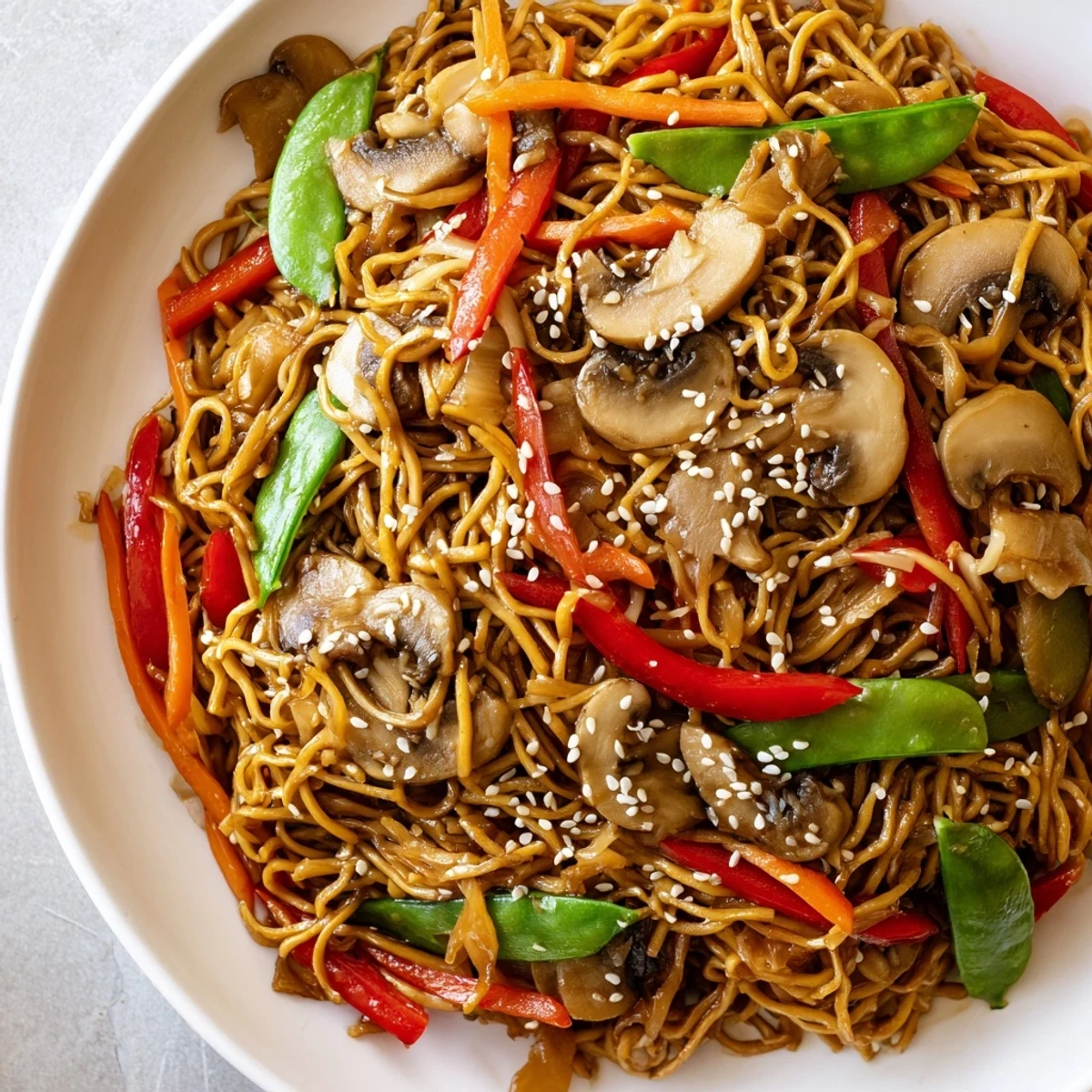 Steaming bowl of vegetarian garlic mushroom chow mein featuring tender egg noodles stir-fried with bell peppers and snap peas