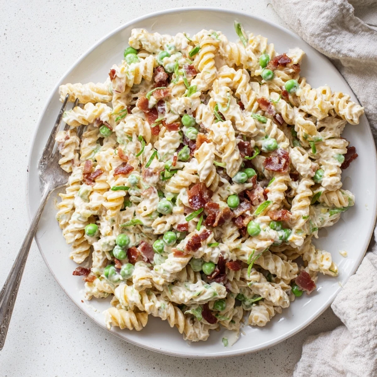 Colorful bowl of addictive pasta salad with bacon, cheese, peas, and green onions