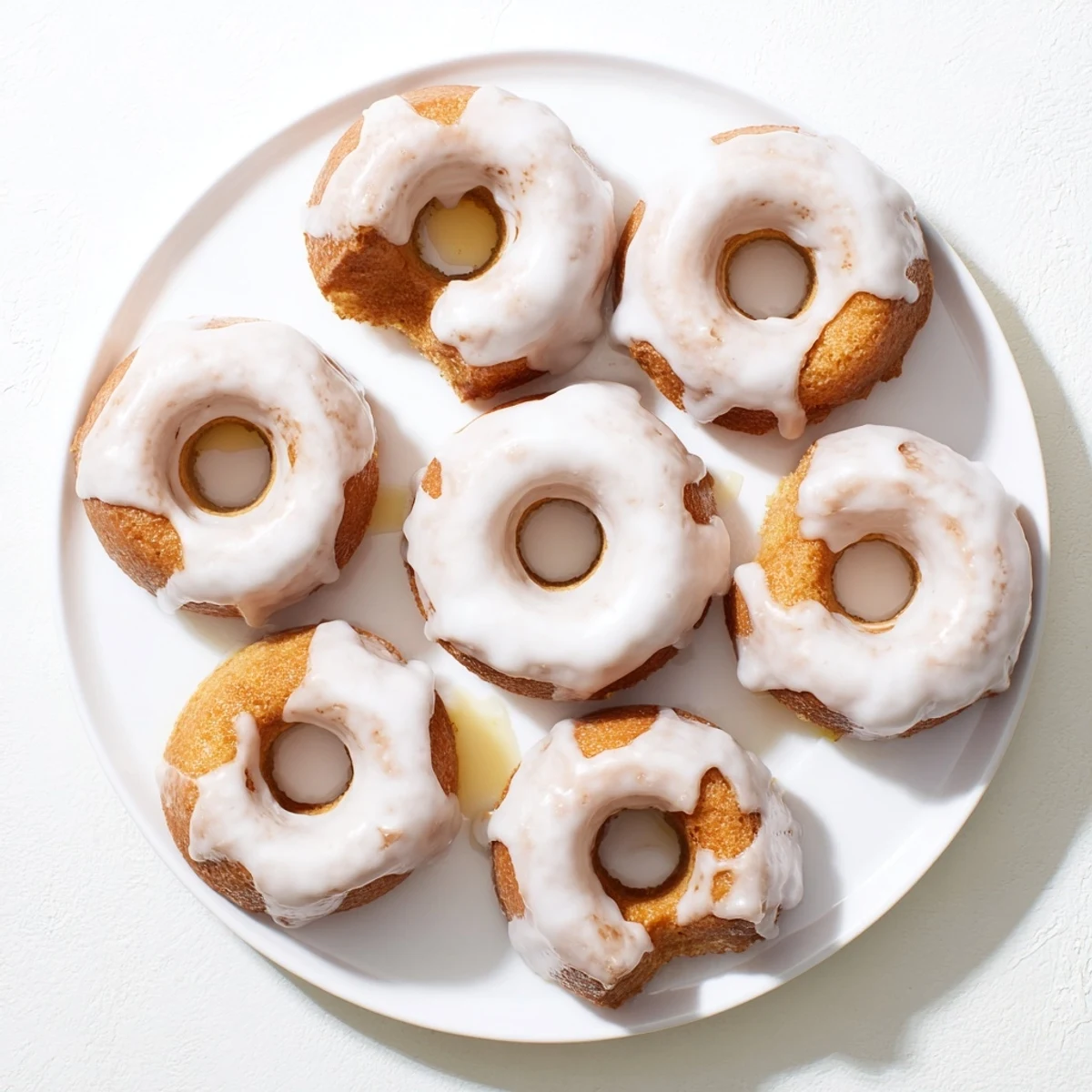 Golden baked Greek yogurt cake donuts topped with sweet vanilla glaze and colorful sprinkles on a white plate