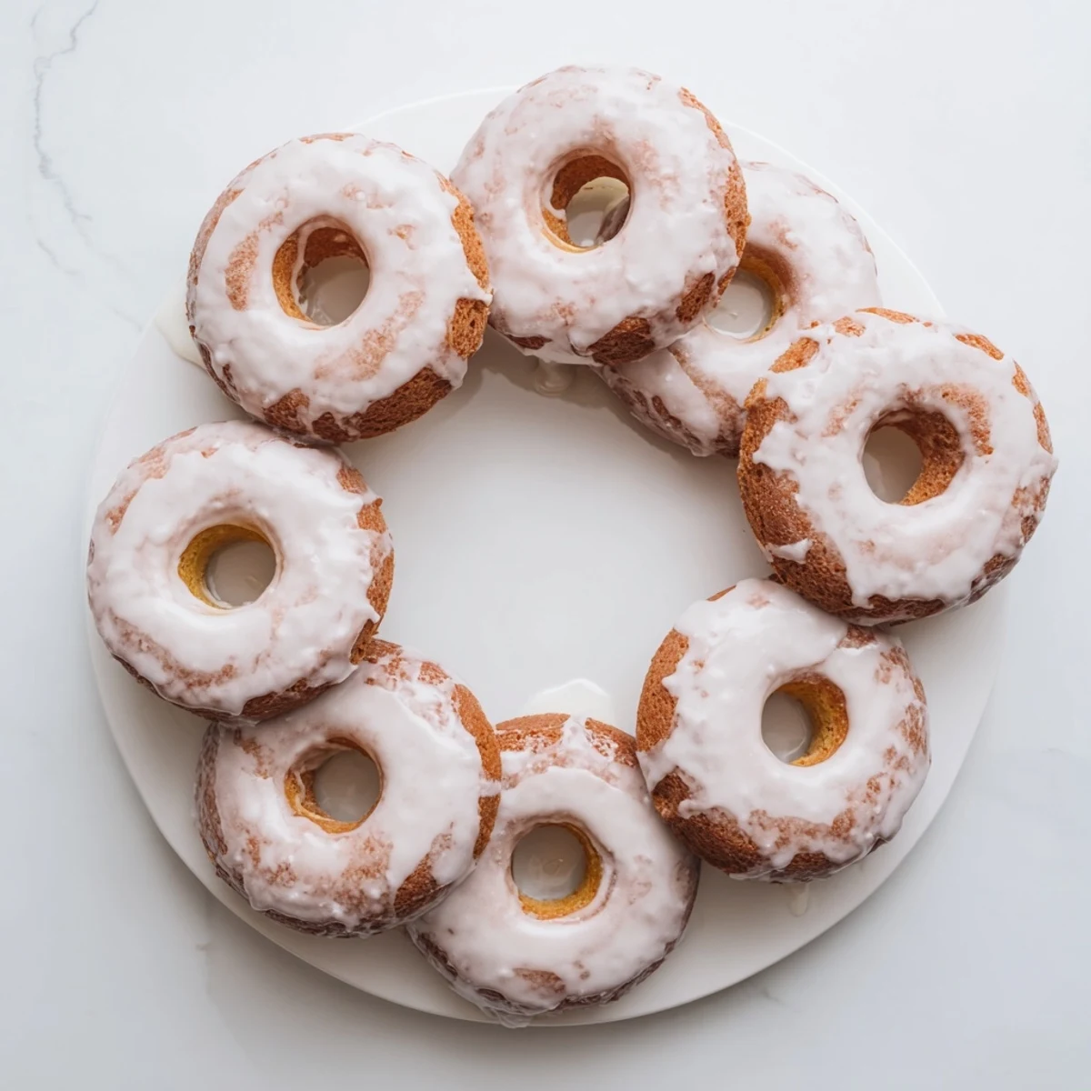 Close up of moist Greek yogurt cake donuts with cinnamon speckled batter and glossy vanilla glaze coating