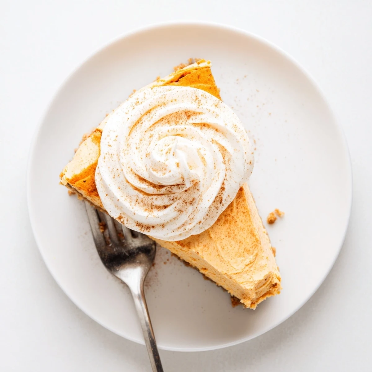 Rich creamy pumpkin spice Christmas cheesecake dessert with dollop of vanilla whipped cream garnish