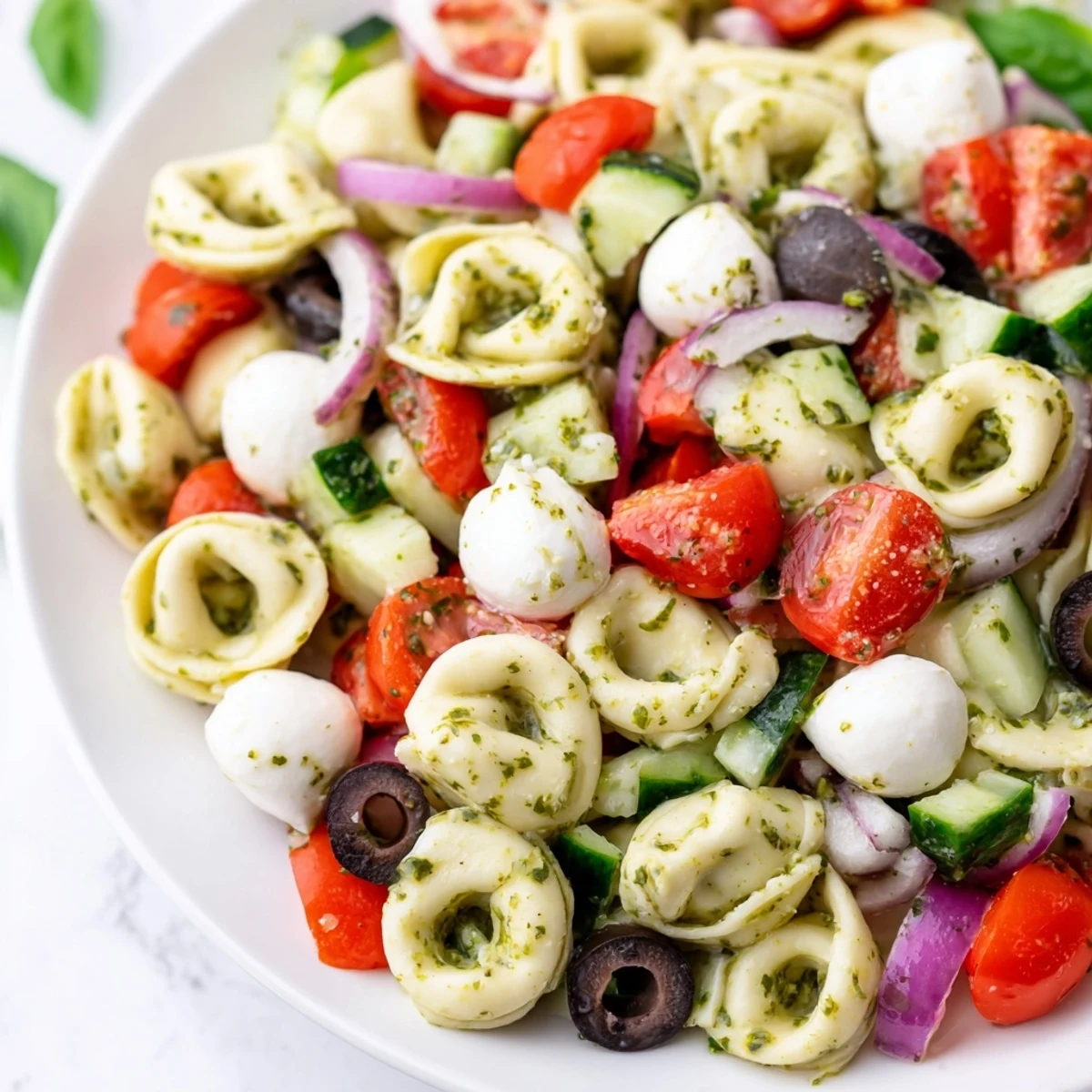 Colorful tortellini pasta salad in a bowl with cherry tomatoes, cucumber, and zesty Italian dressing