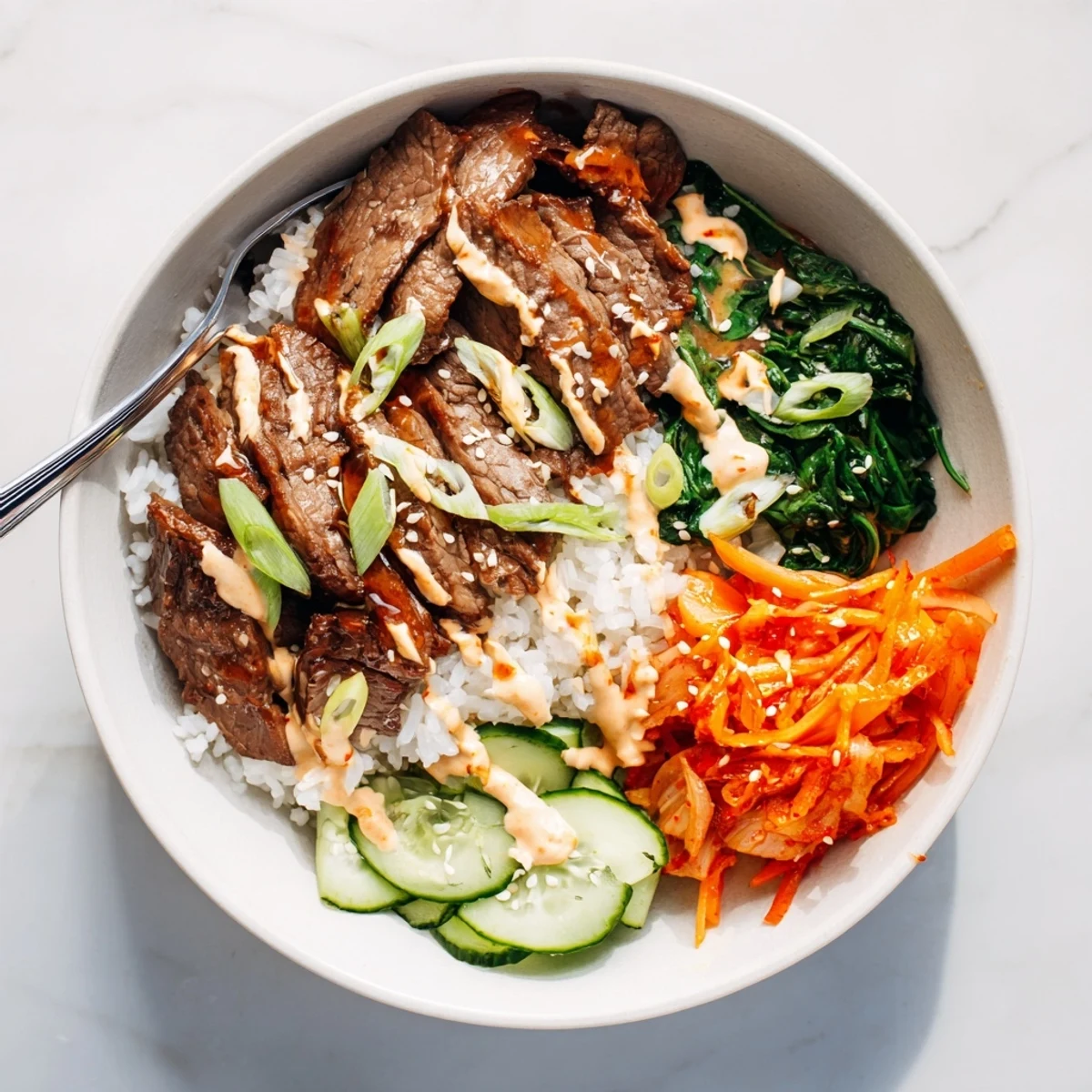 Sliced marinated steak over fluffy rice drizzled with spicy cream sauce in Korean BBQ Steak Rice Bowls