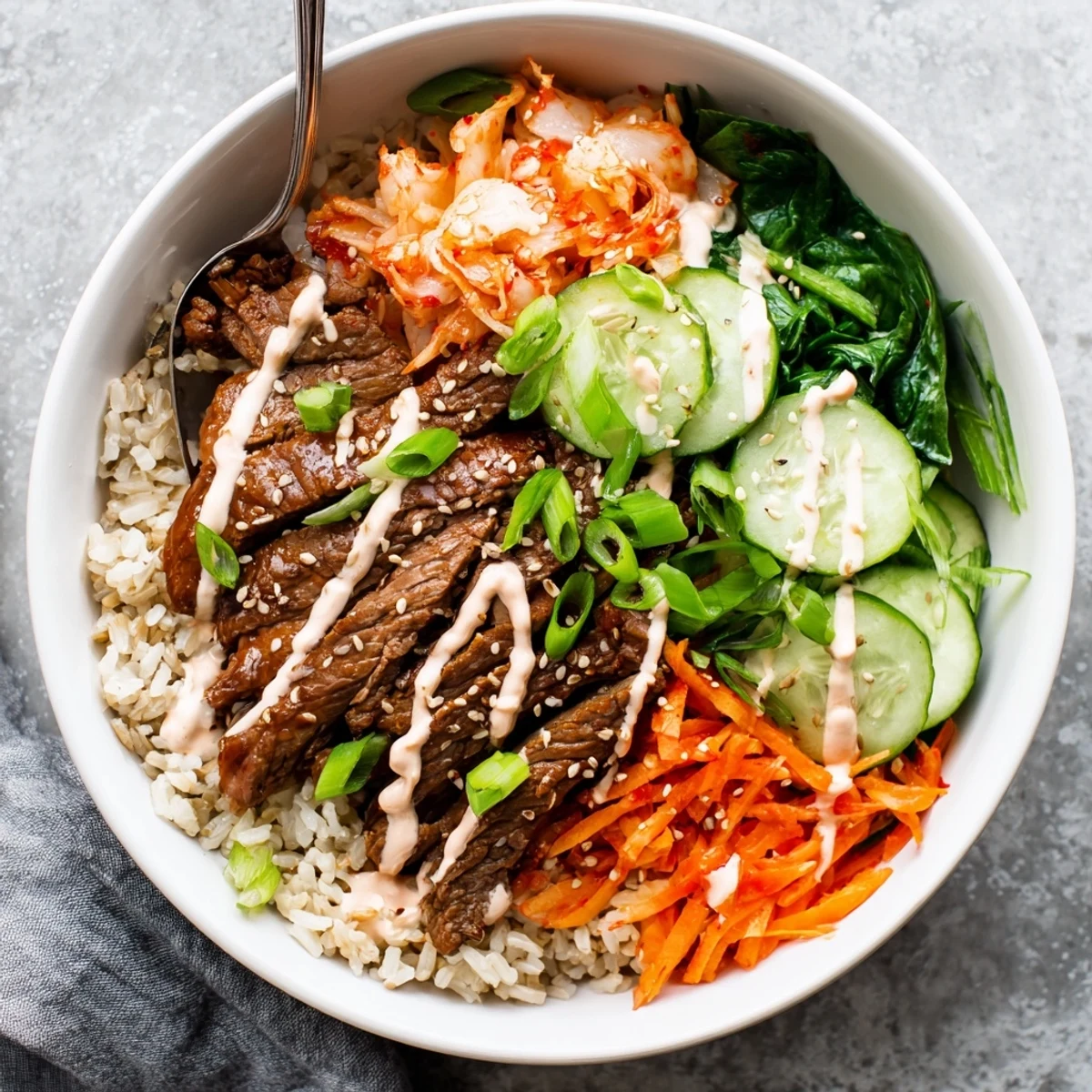 A generous bowl of Korean BBQ Steak Rice Bowls with tender steak, shredded carrots, and bold spicy mayo