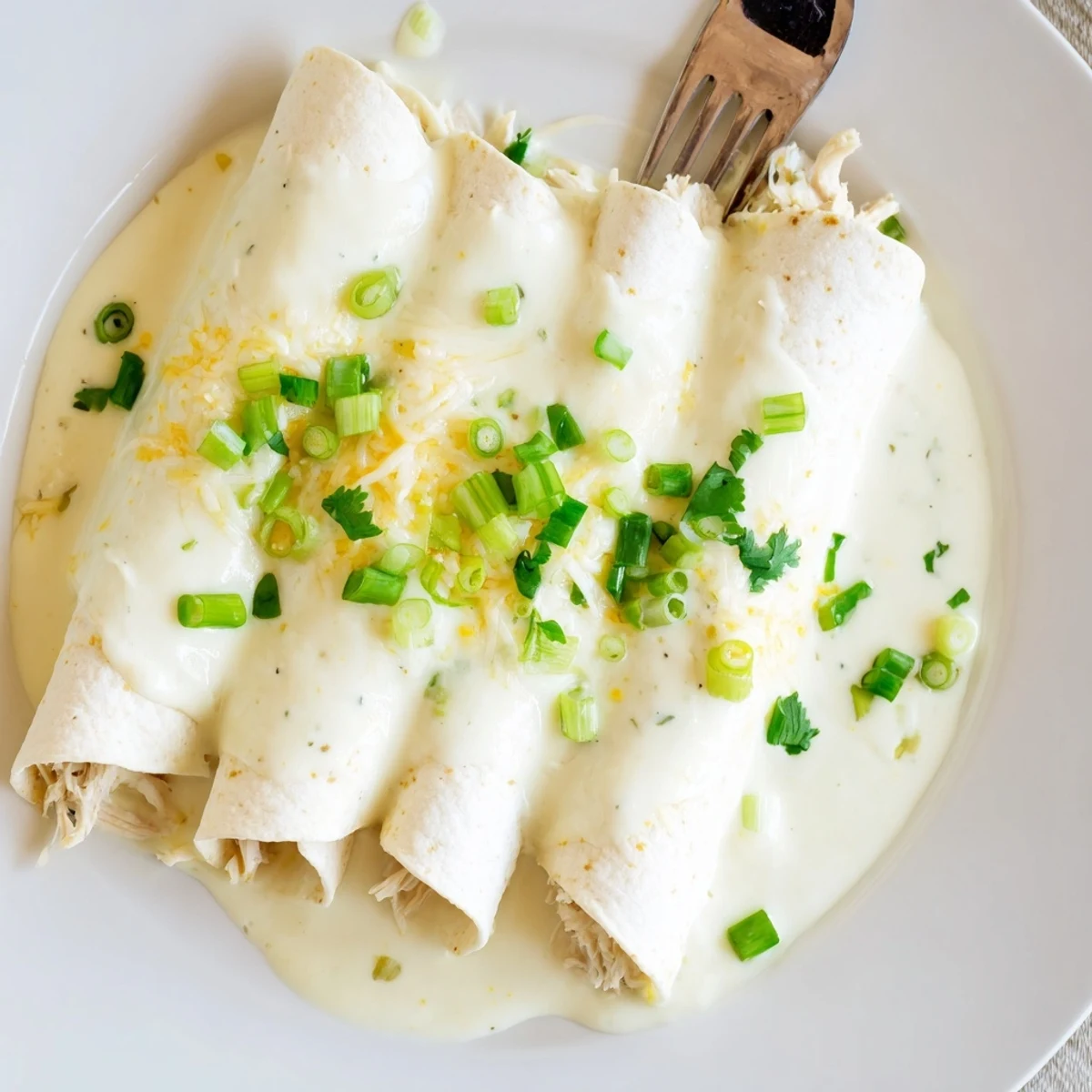 Creamy White Chicken Enchiladas bubbling in dish, golden edges and melted cheese.