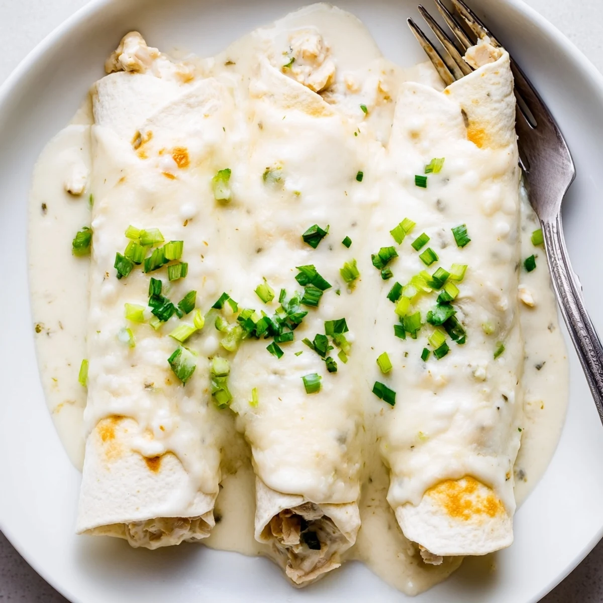 Topped with cilantro, Creamy White Chicken Enchiladas served with rice, steamy and comforting.
