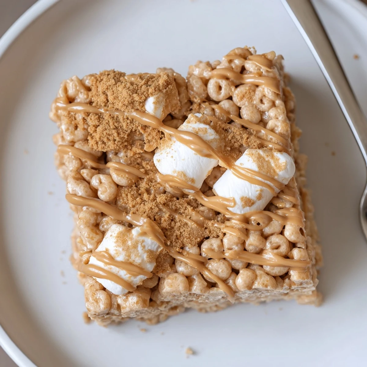Warm Biscoff Rice Krispie Treats pressed into pan, sticky, crunchy edges.