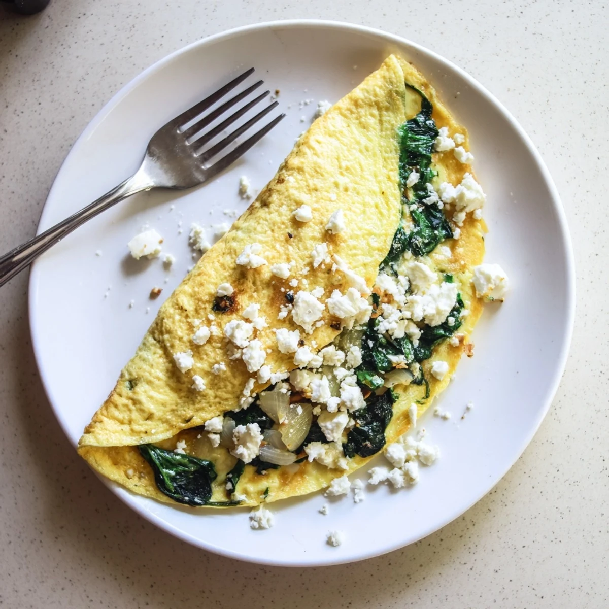 Breakfast skillet featuring spinach feta omelet with golden edges and savory cheesy spinach filling spilling out