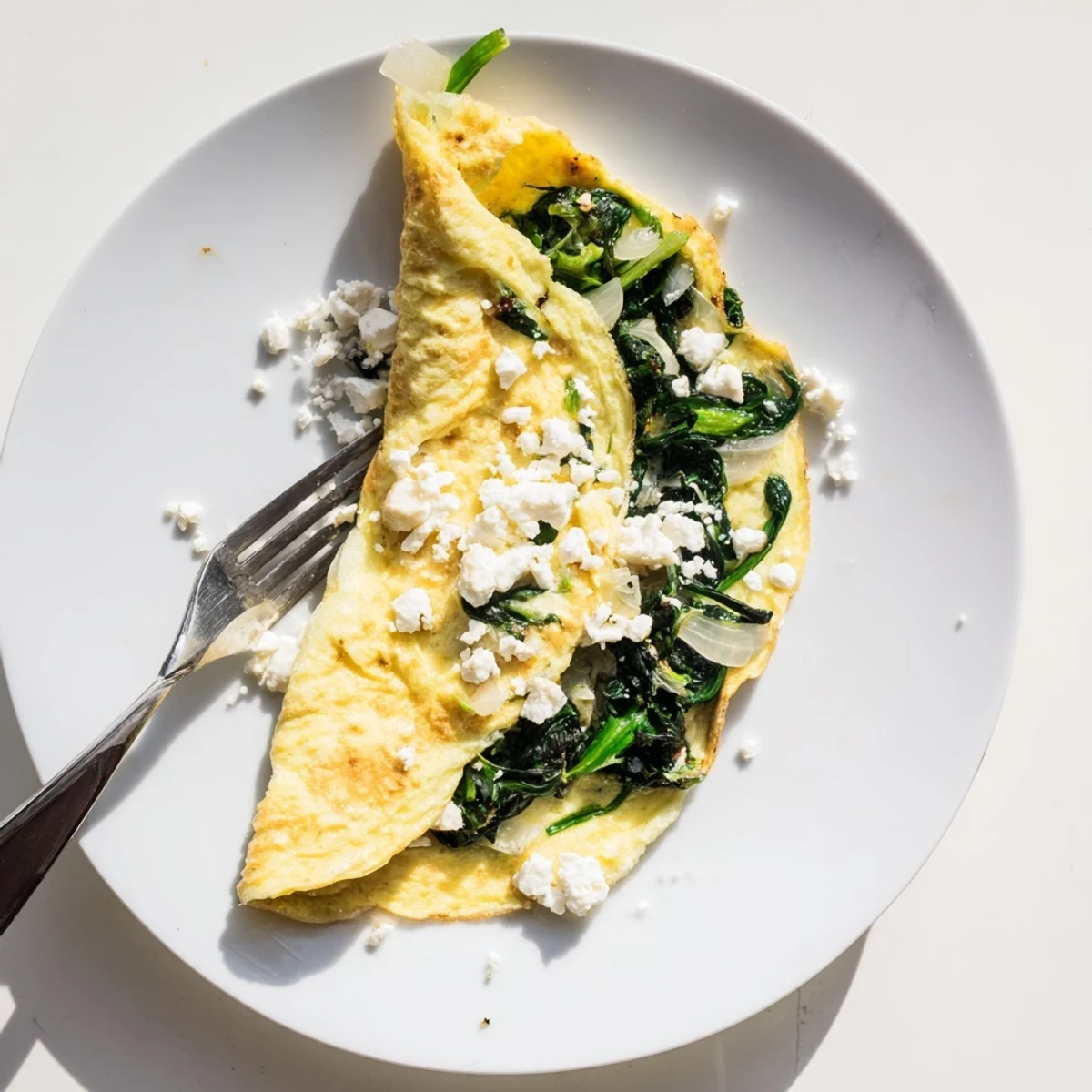 Fluffy Mediterranean style omelet recipe showcasing vibrant green spinach chunks and salty feta crumbles on top