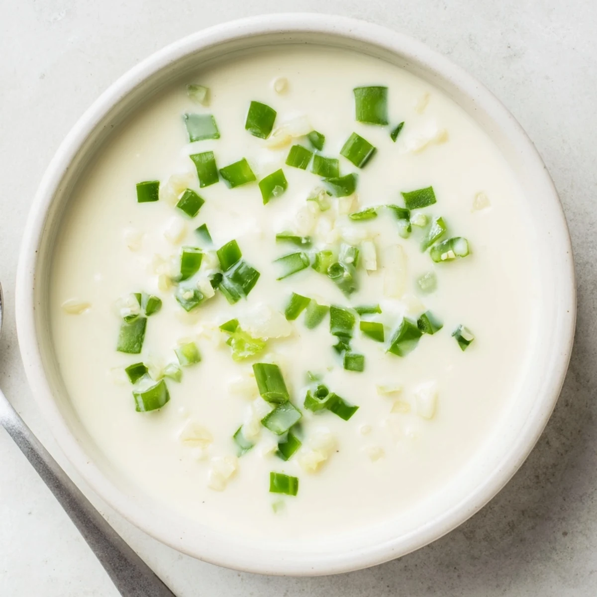 Rich white queso dip served warm in a bowl with crispy tortilla chips