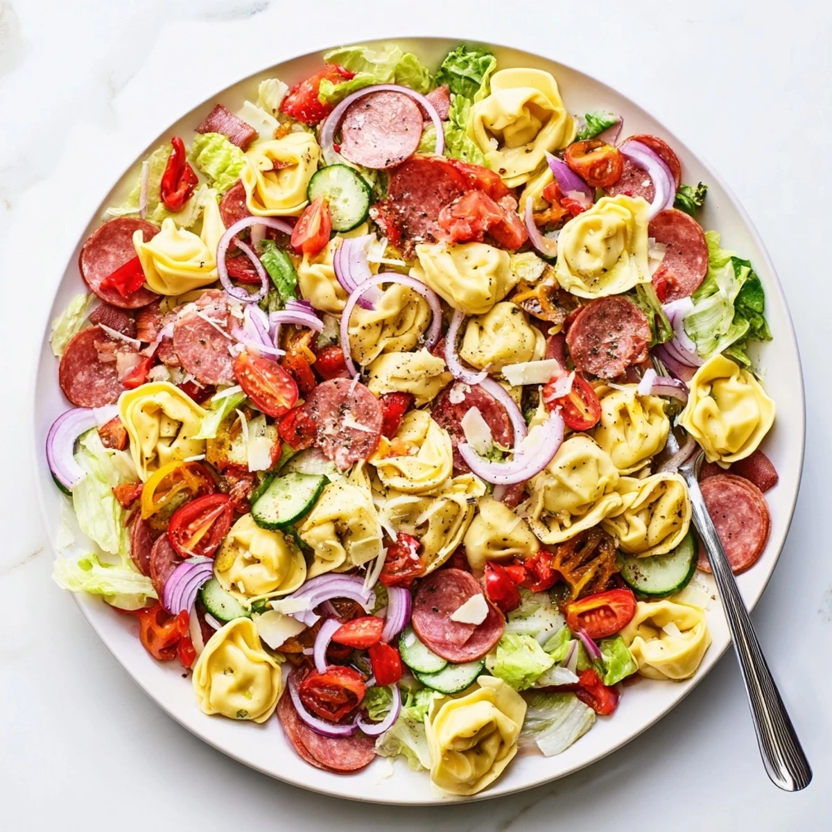 Hearty tortellini pasta salad featuring roasted red peppers, pepperoncini, cherry tomatoes, and cubed provolone tossed in tangy herb vinaigrette