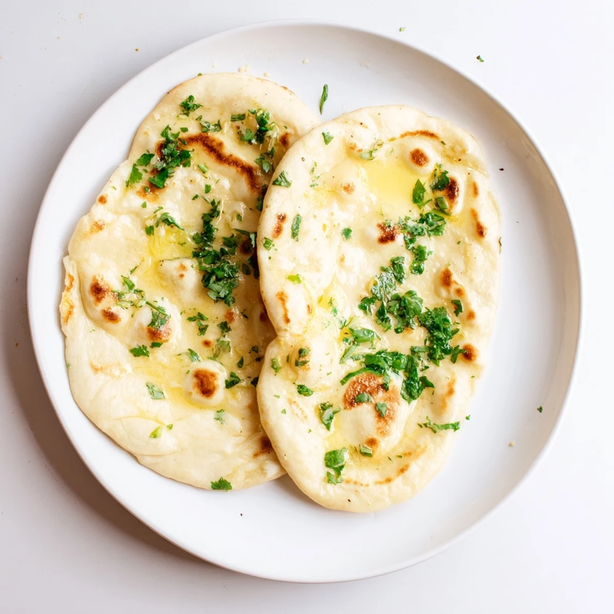 Golden brown sourdough discard naan brushed with melted butter and fresh cilantro on a wooden board