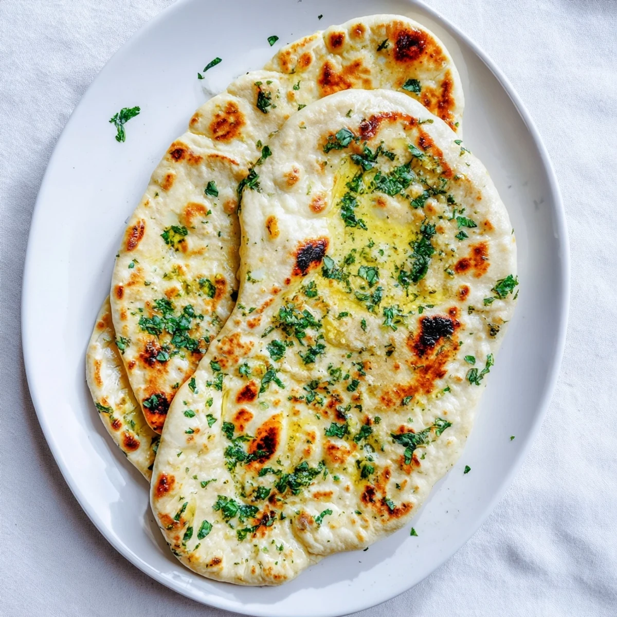 Warm homemade naan bread flecked with garlic and nigella seeds, fresh from a hot cast iron skillet