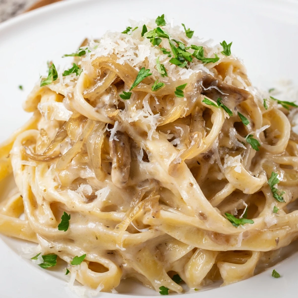 A steaming bowl of caramelized onion cream pasta featuring golden onions and silky white sauce
