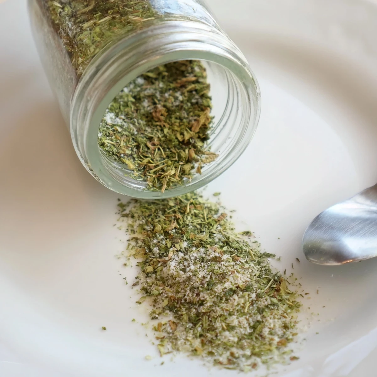 A jar of homemade Dehydrated Tzatziki Seasoning Mix beside fresh herbs on a rustic wooden board