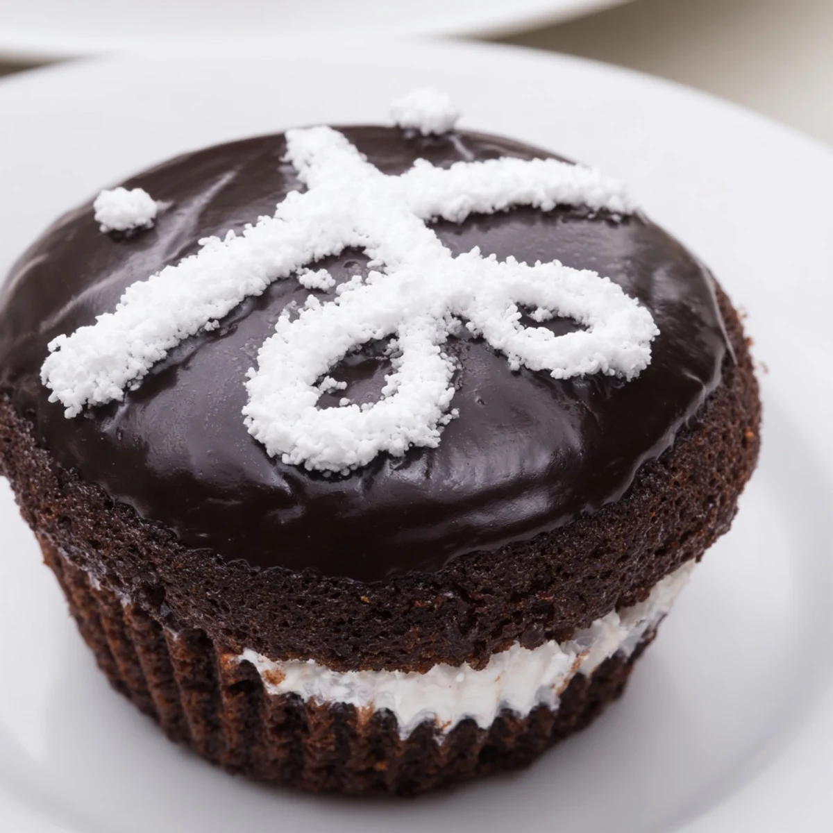 Homemade Hostess Cupcakes with glossy chocolate ganache and piped white icing swirls