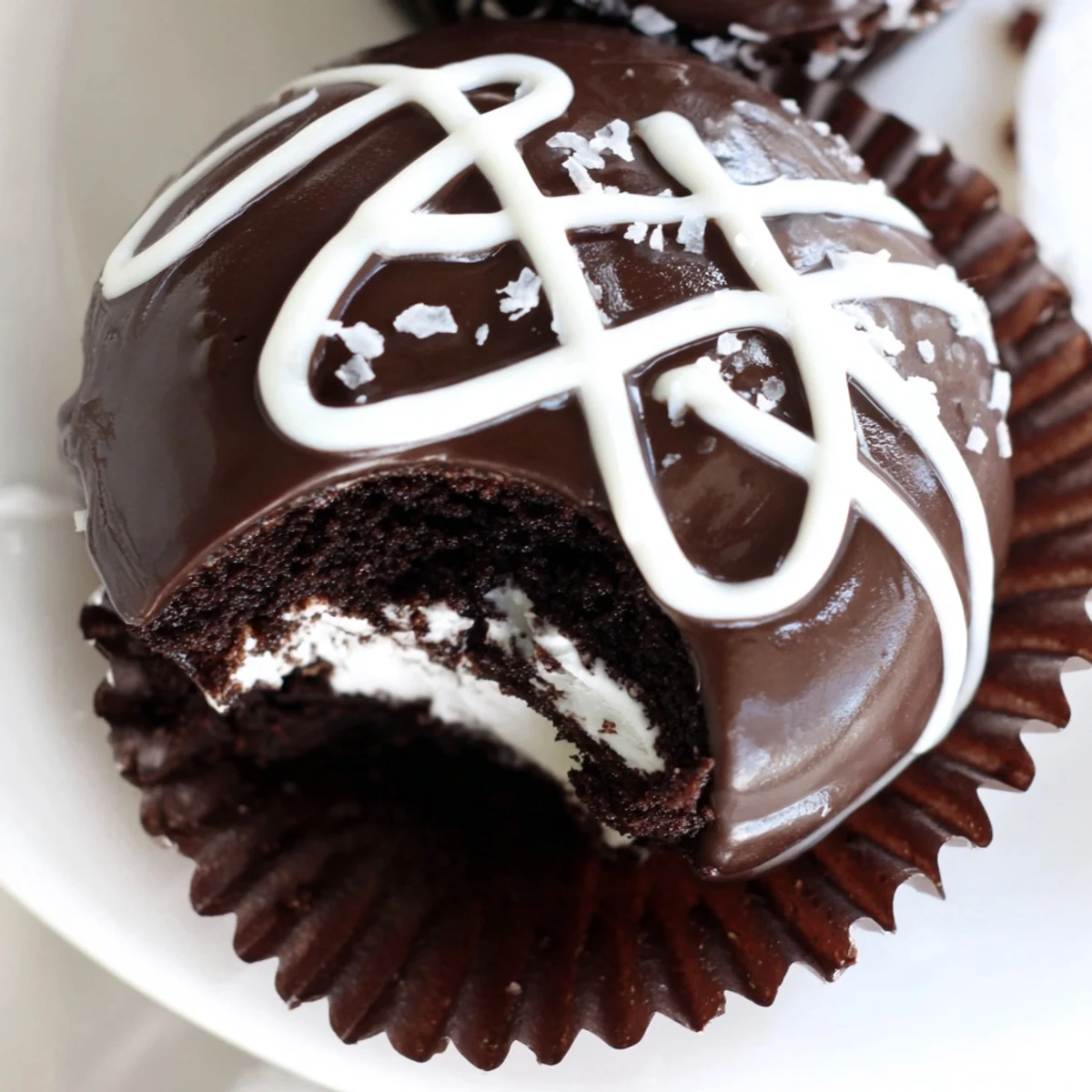 Cream-filled Homemade Hostess Cupcakes topped with shiny glaze on a wire cooling rack