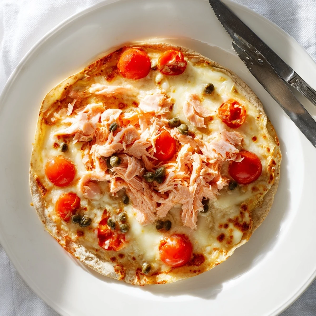 Crispy baked leftover salmon tortilla pizza loaded with capers, red onion, and melted cheese.