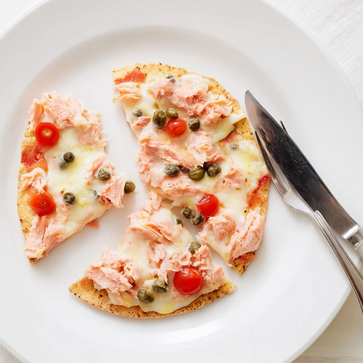 A leftover salmon tortilla pizza with melted mozzarella, cherry tomatoes, and fresh dill.