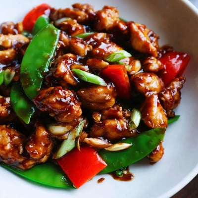 Golden brown stir-fried Chinese garlic chicken tossed with crisp bell peppers and snow peas