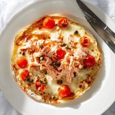 Crispy baked leftover salmon tortilla pizza loaded with capers, red onion, and melted cheese.